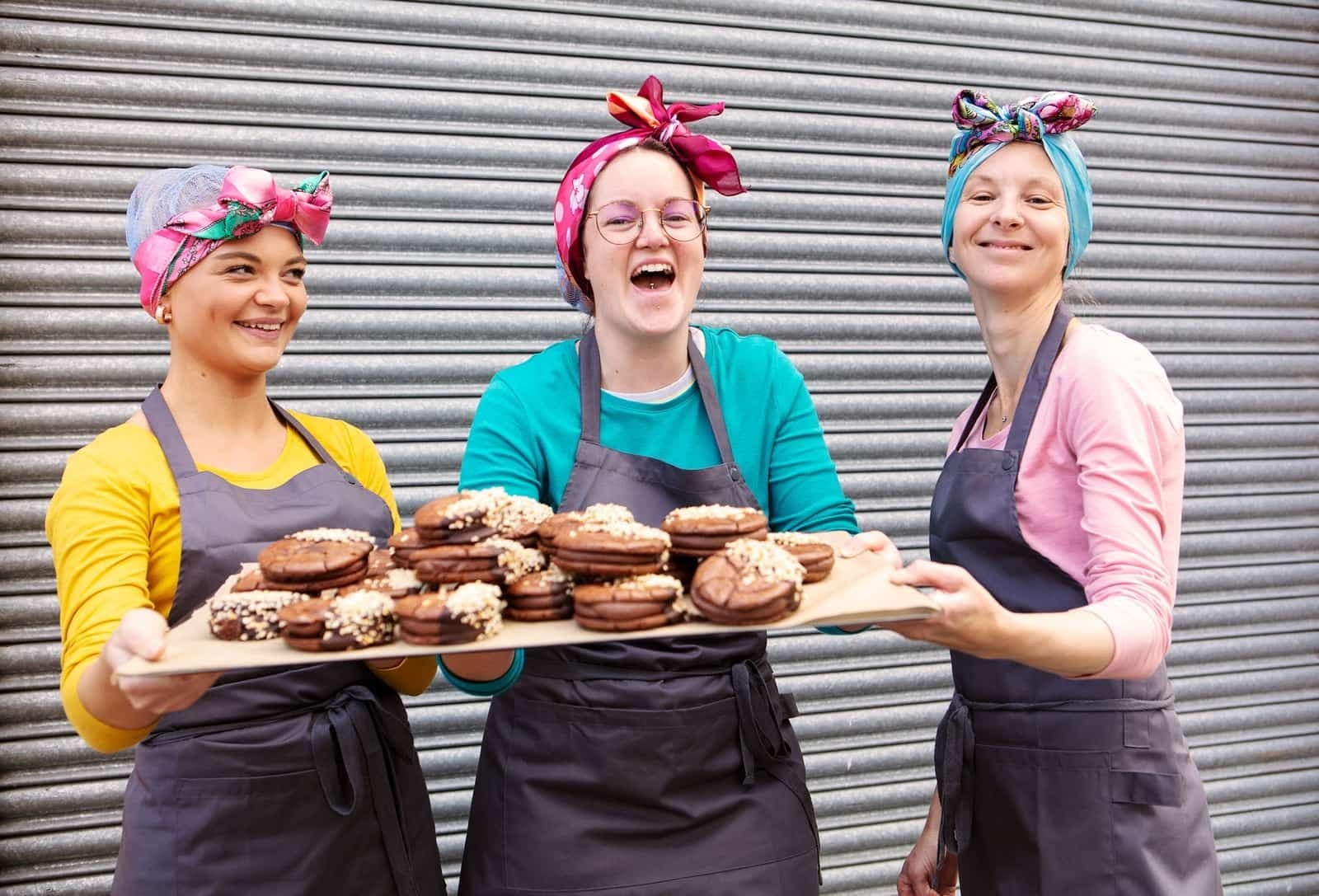 Image of the Bakers at Cake Stories holding a board of their cakes.