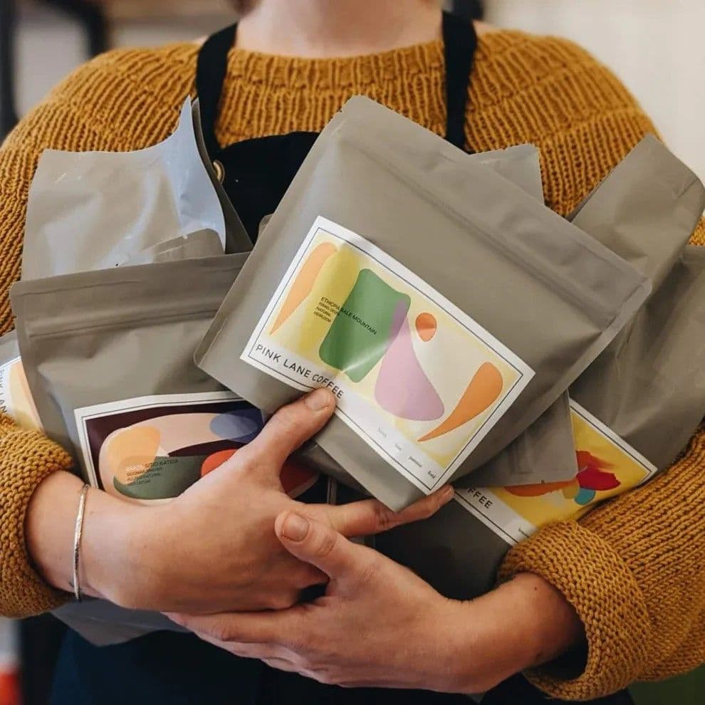 Image of a person holding a bag of pink lane coffee.