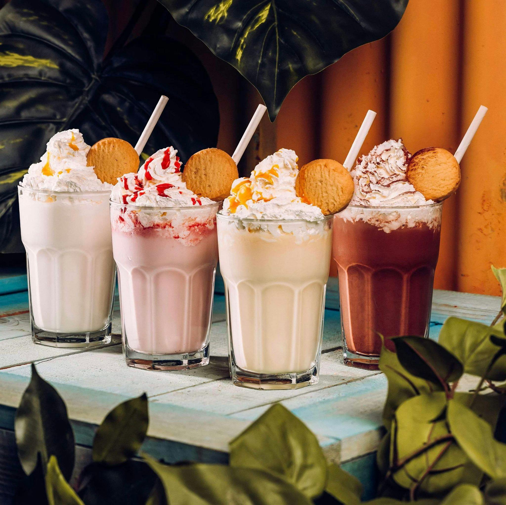 4 milkshakes lined up on a table.