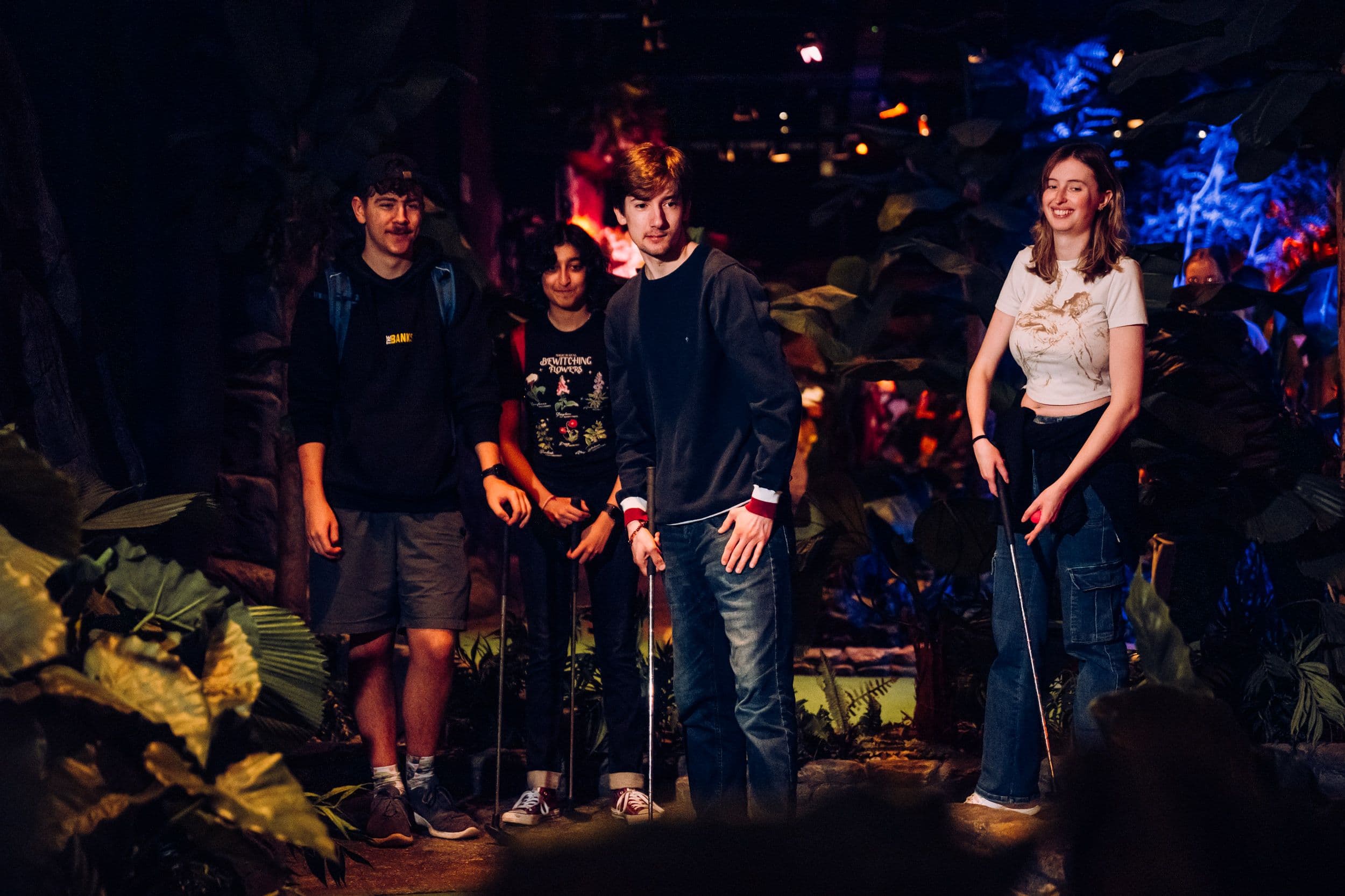 Four teenagers playing mini golf