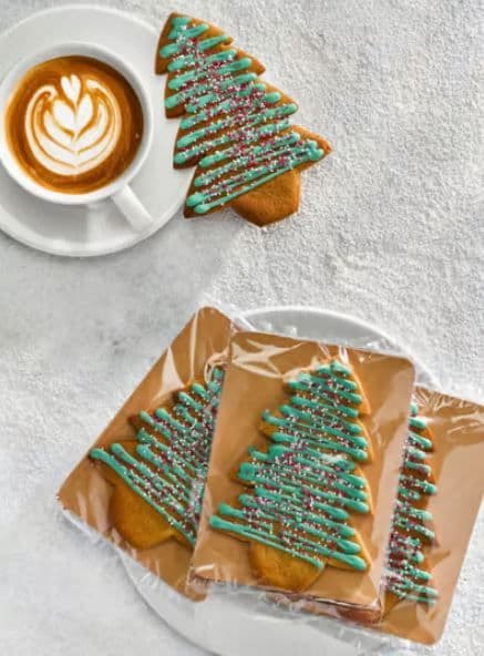 Gingerbread Christmas trees displayed next to a cup of coffee.