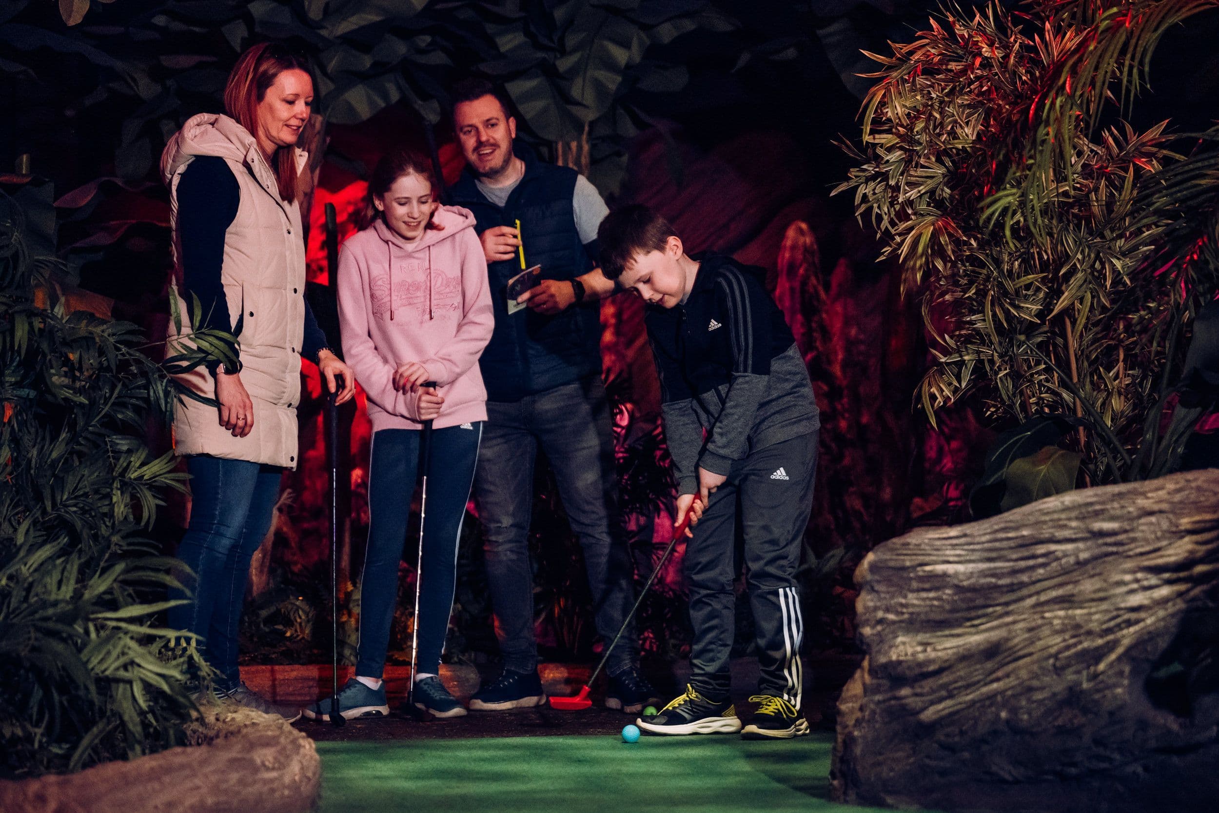 A family of four playing golf and smiling.