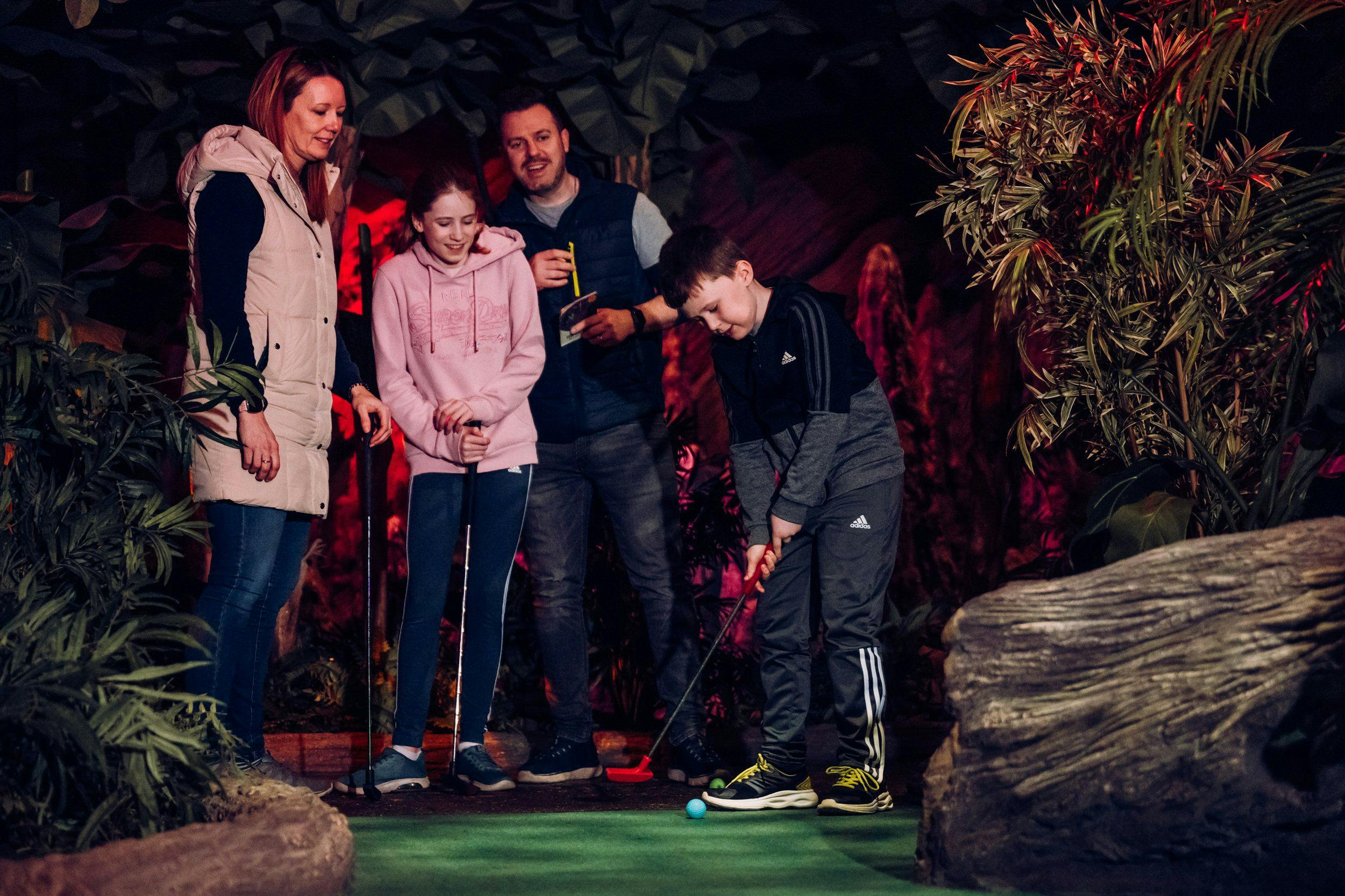 A family of 4 playing mini golf.