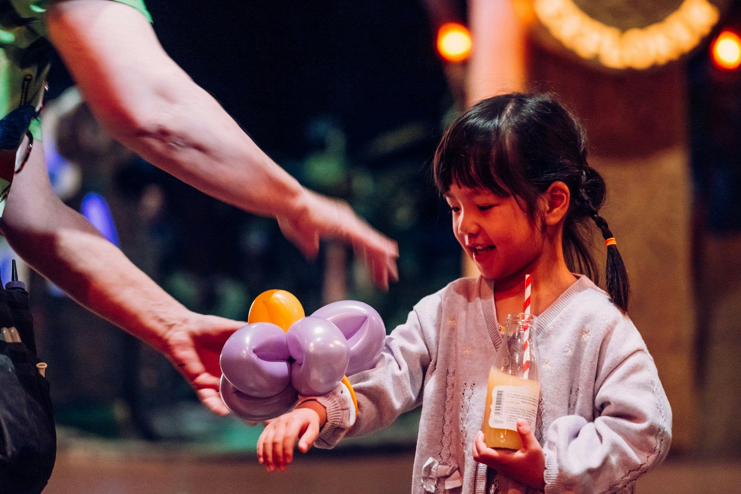 A girl receiving a balloon animal.