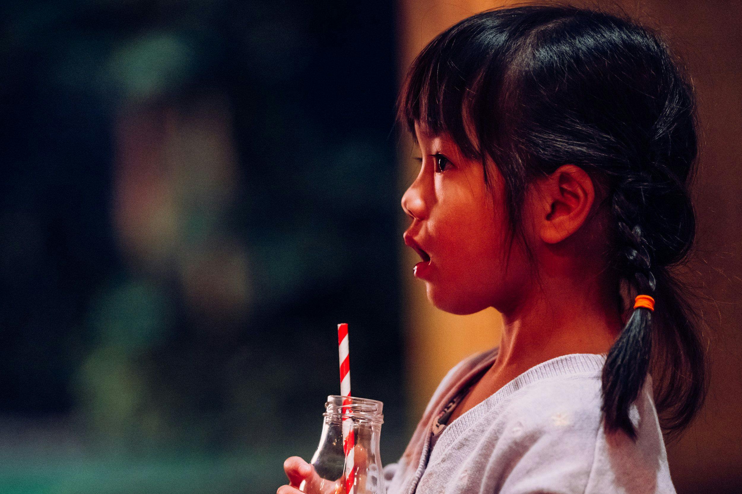 A young girl drinks with a straw.