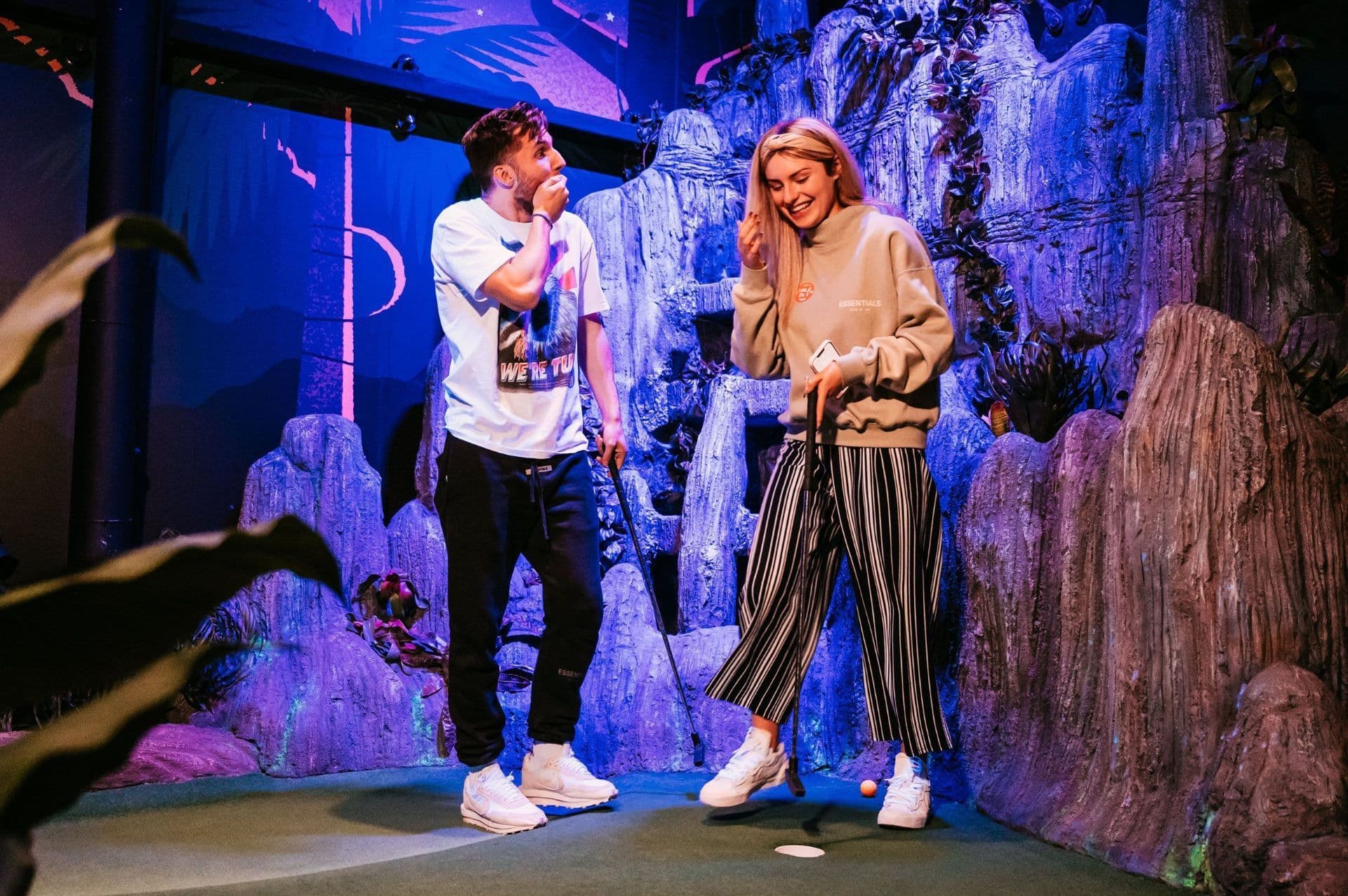 Young Couple Playing Mini Golf and Smiling at Treetop Golf.