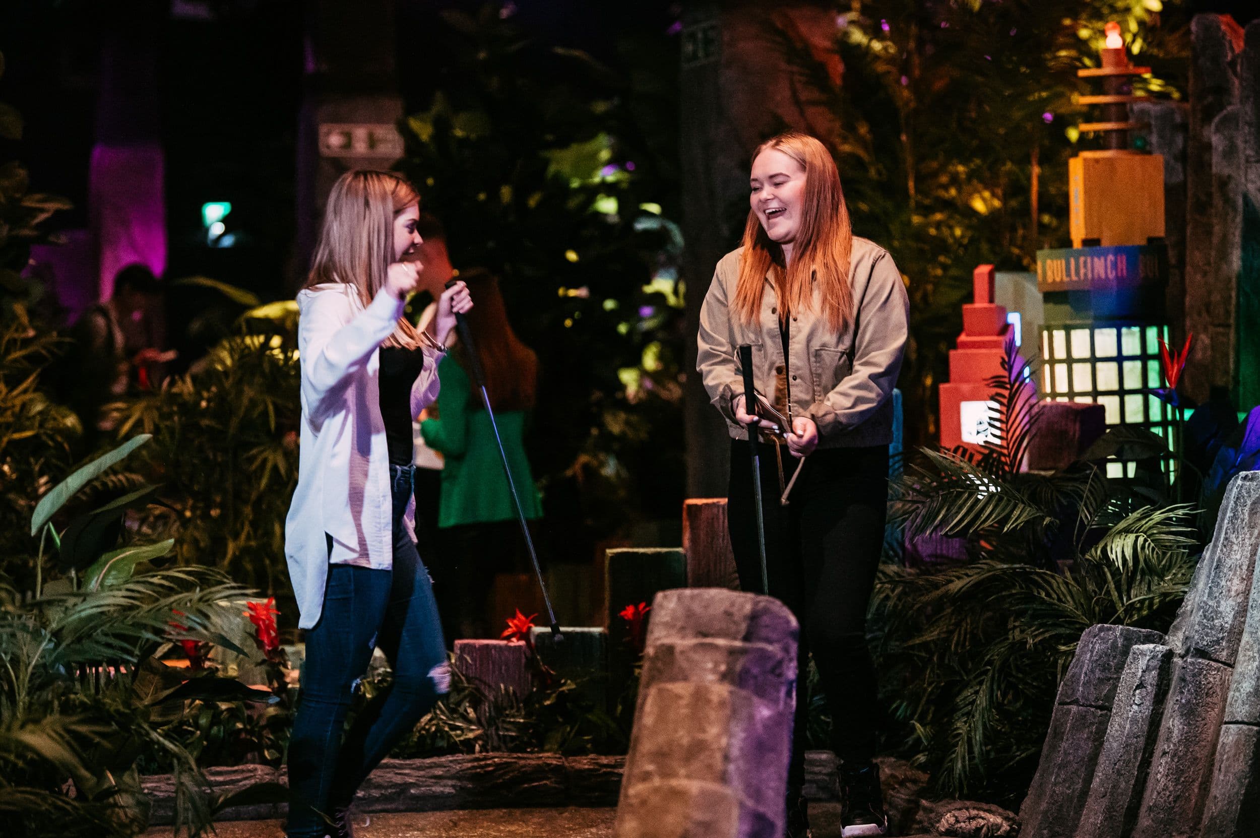 Two Girls laughing playing mini golf.