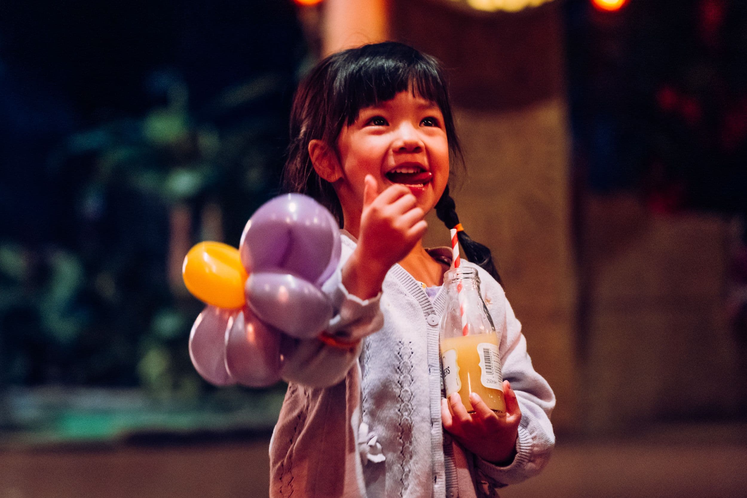 A small child smiles as she holds a balloon animal at Treetop Golf.