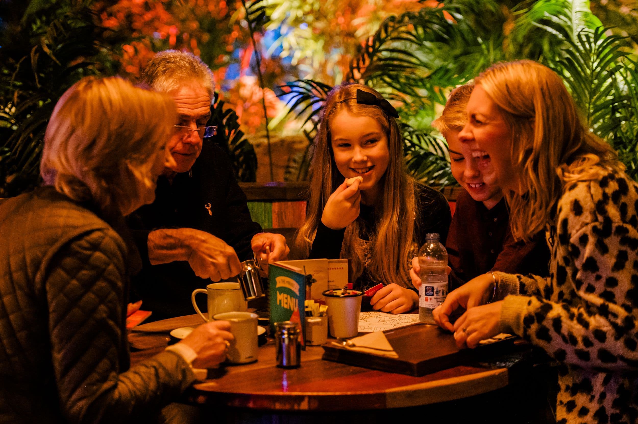 A family laughing and eating at the Market in Treetop Golf.