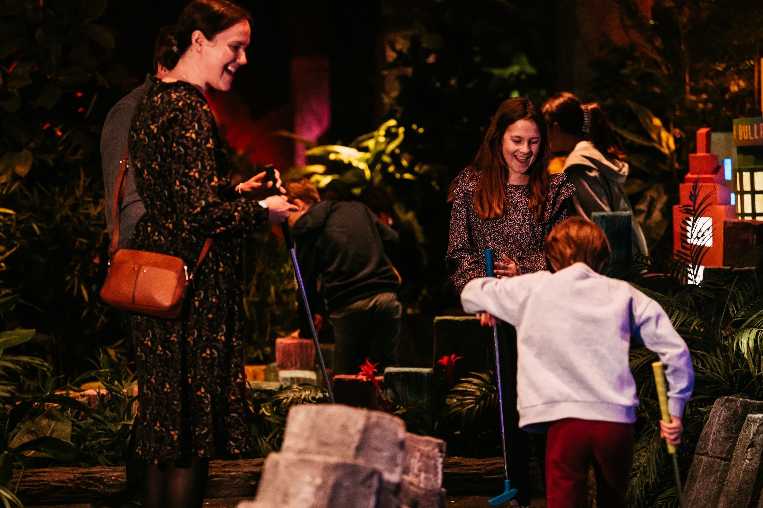 A Child celebrating while his family smiles at Treetop Golf.
