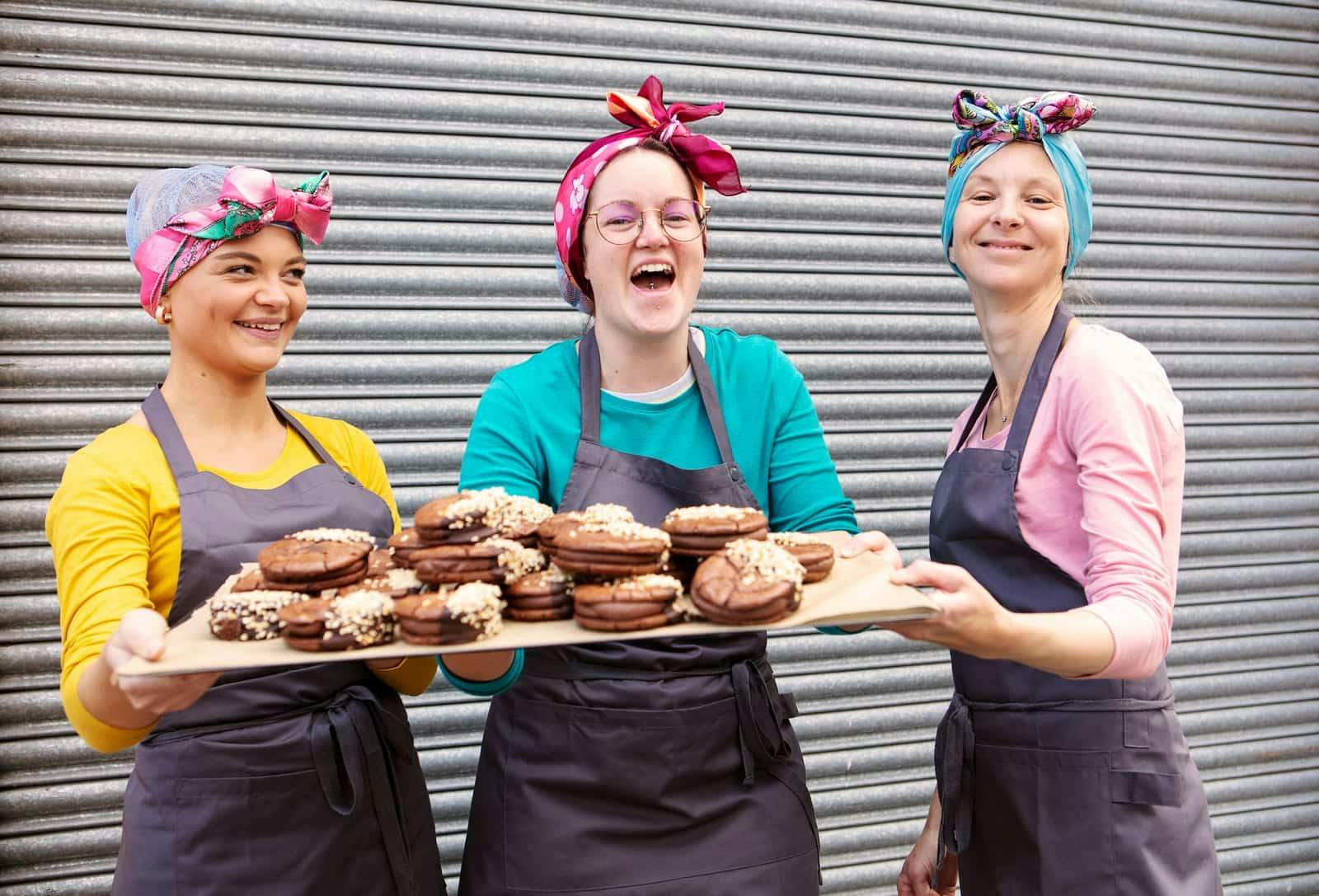 Image of the Bakers at Cake Stories holding a board of their cakes.