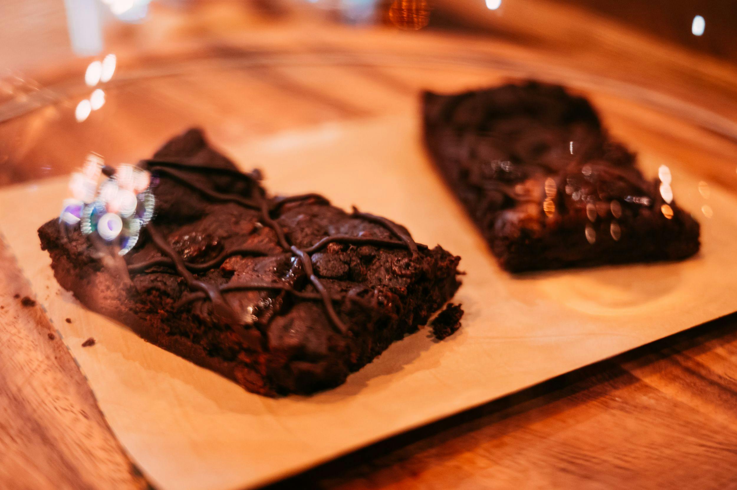 Image of two deep chocolate brownies on a wooden tray. 
