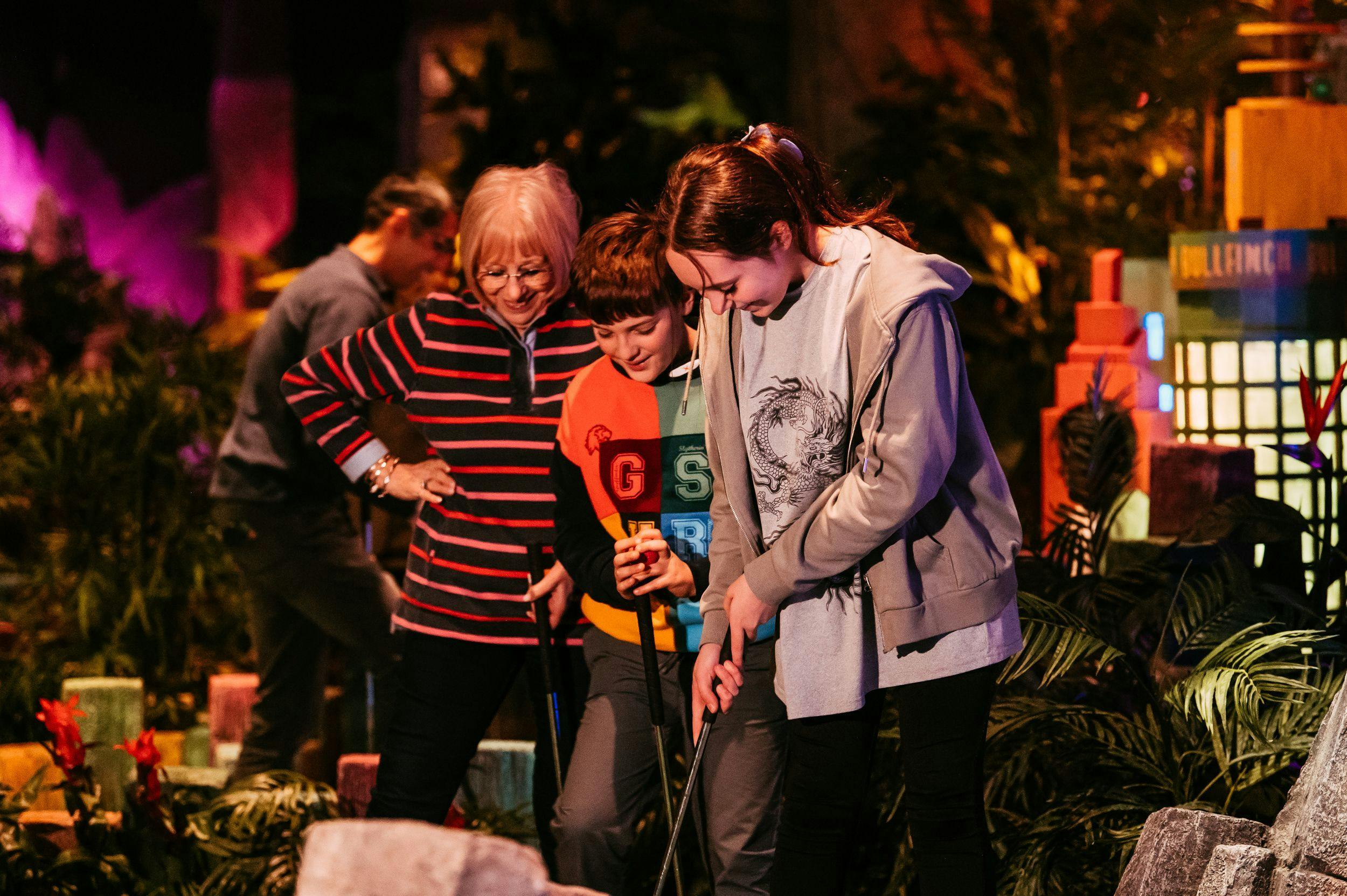 Family of 3 playing mini golf and smiling