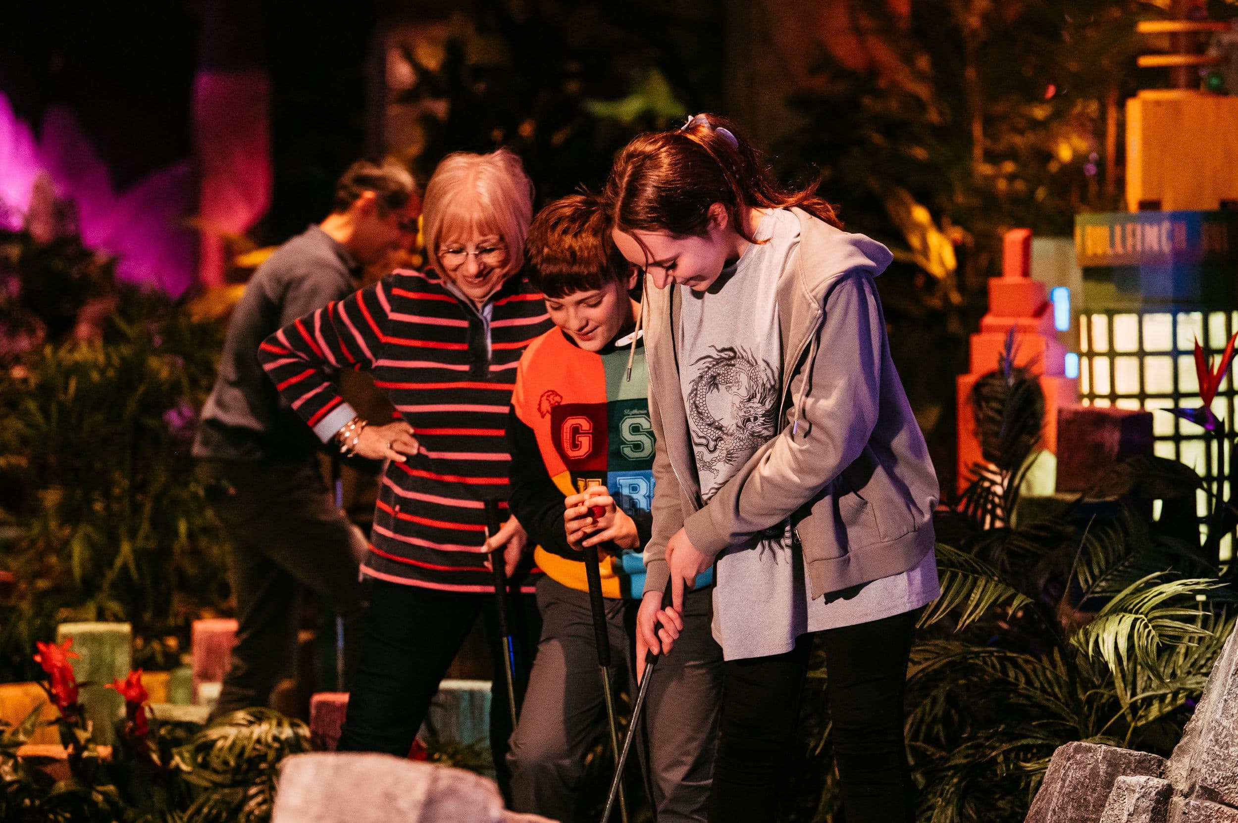 Family of 3 playing mini golf and smiling