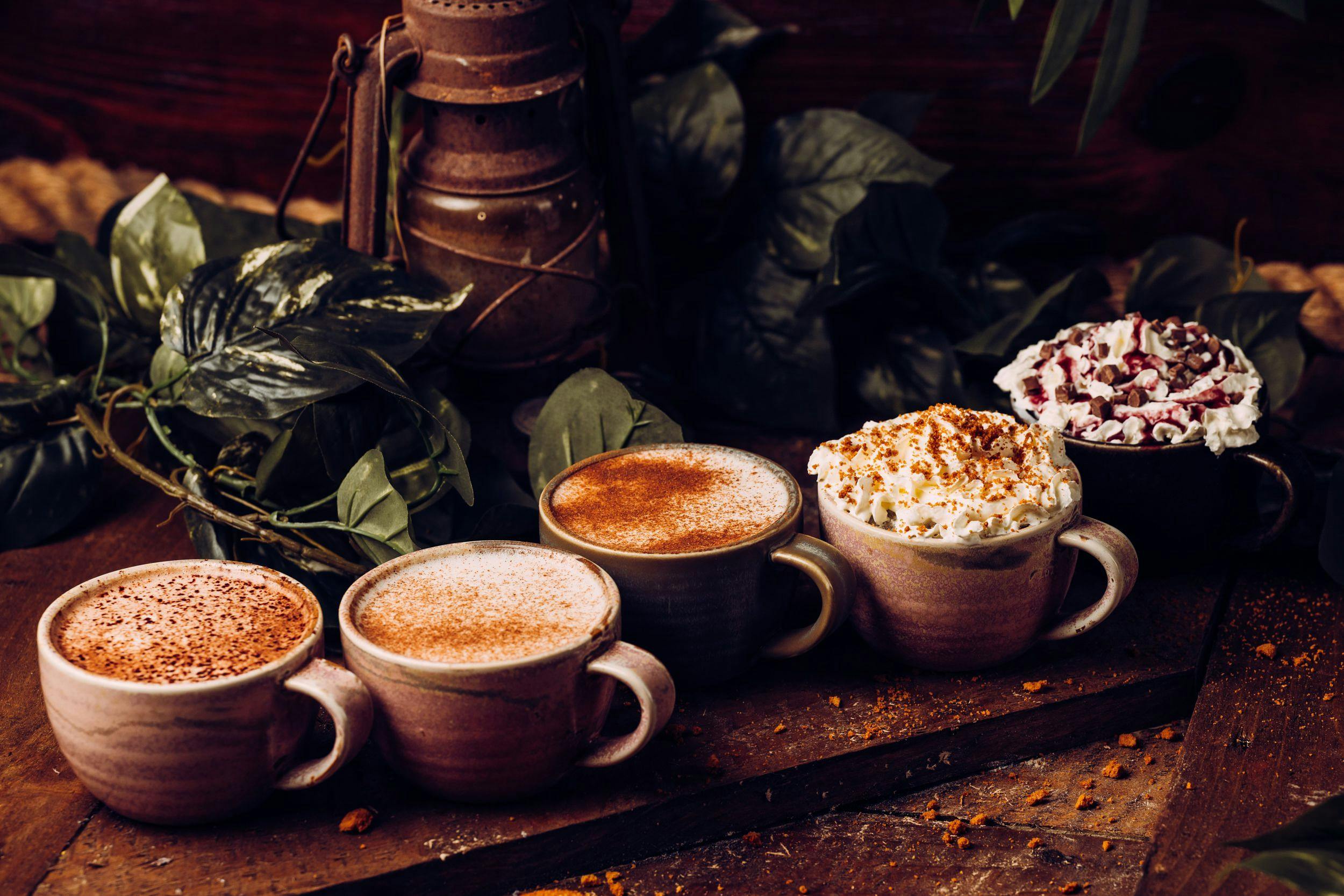 Five festive hot drinks lined up on a table.