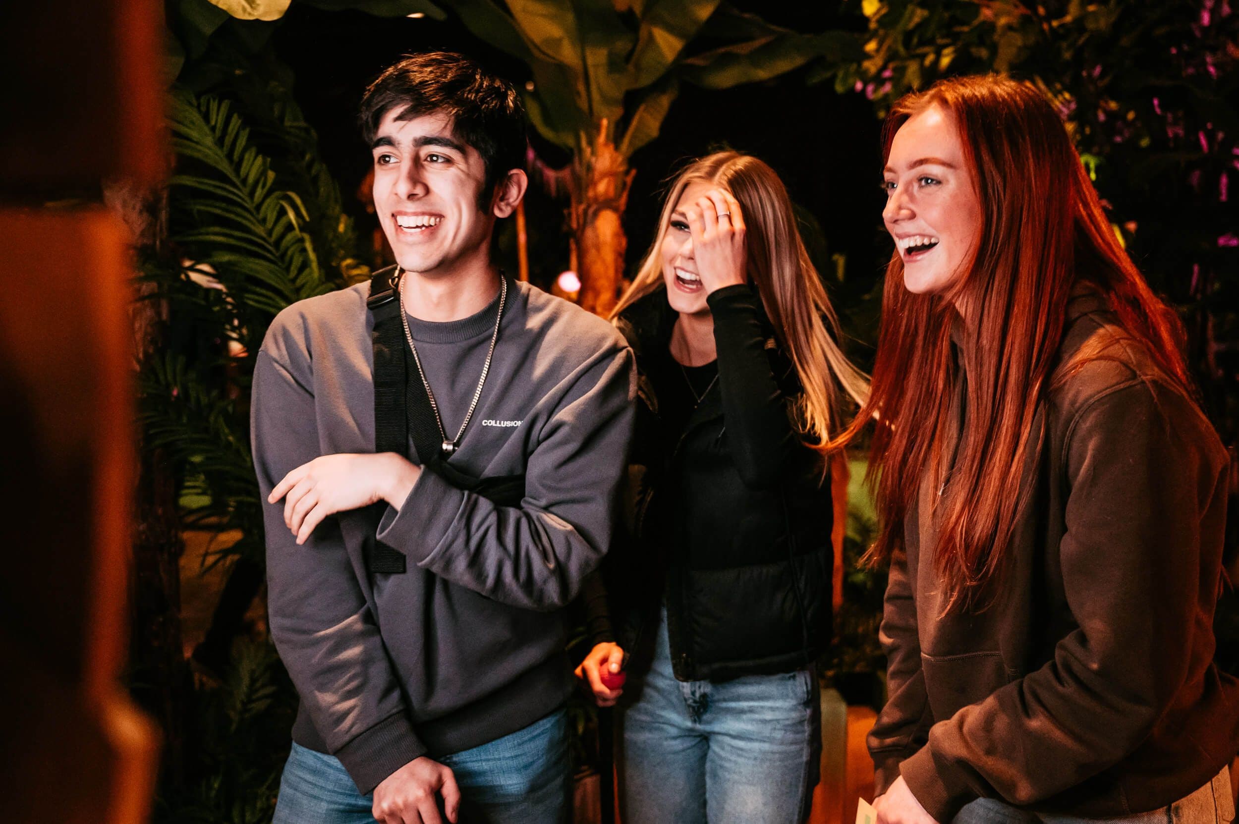 Two early twenties women and a man laugh as they make their way through the Treetop jungle.