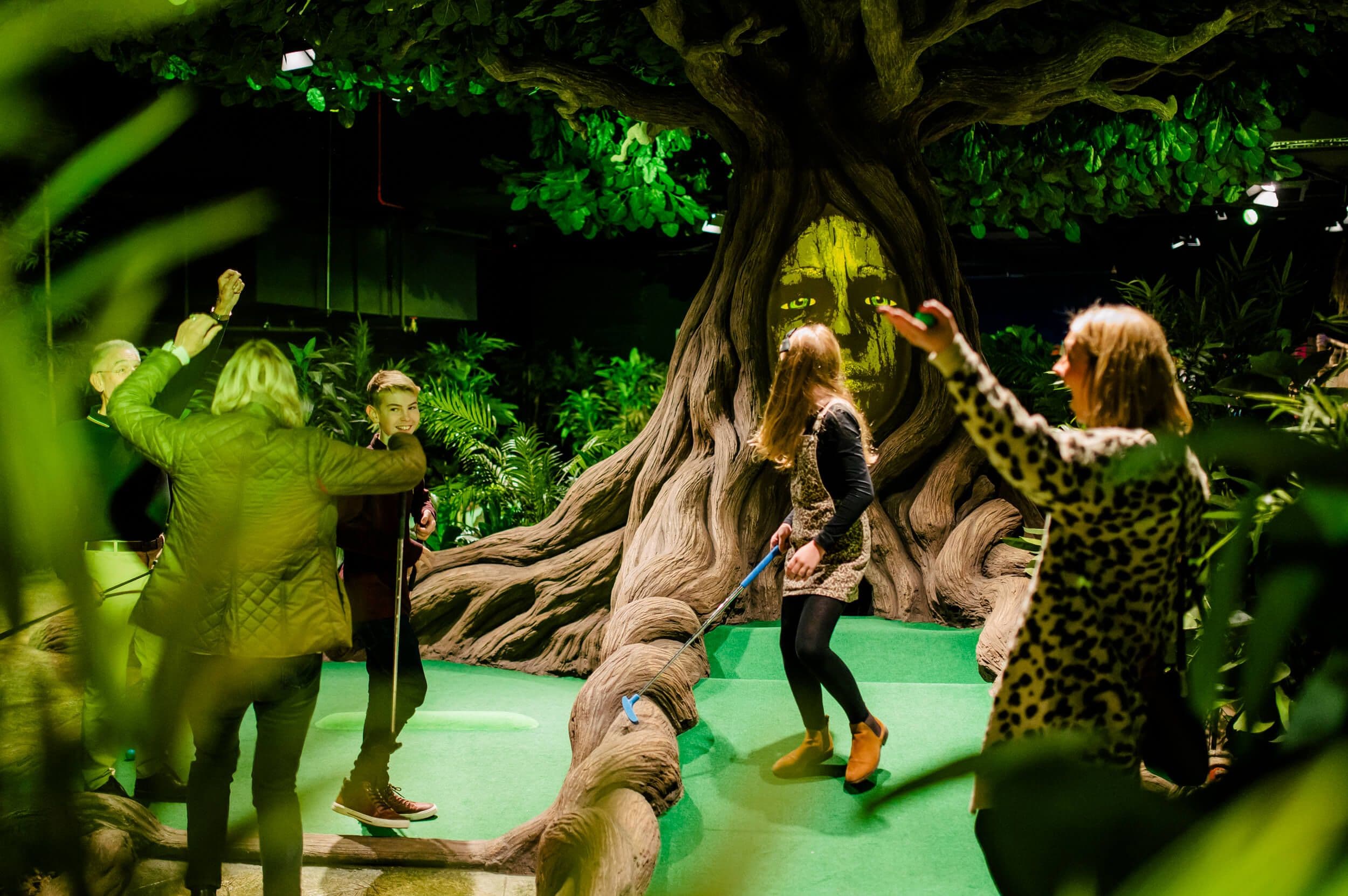 A group of children play in the Mystic Wood, climbing and laughing on the roots of the Mighty Oracle.