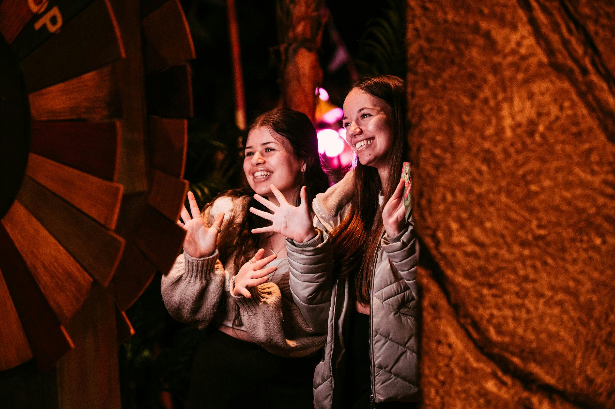Two young women put their hands up and laugh while taking a picture in the free Treetop photobooth. 