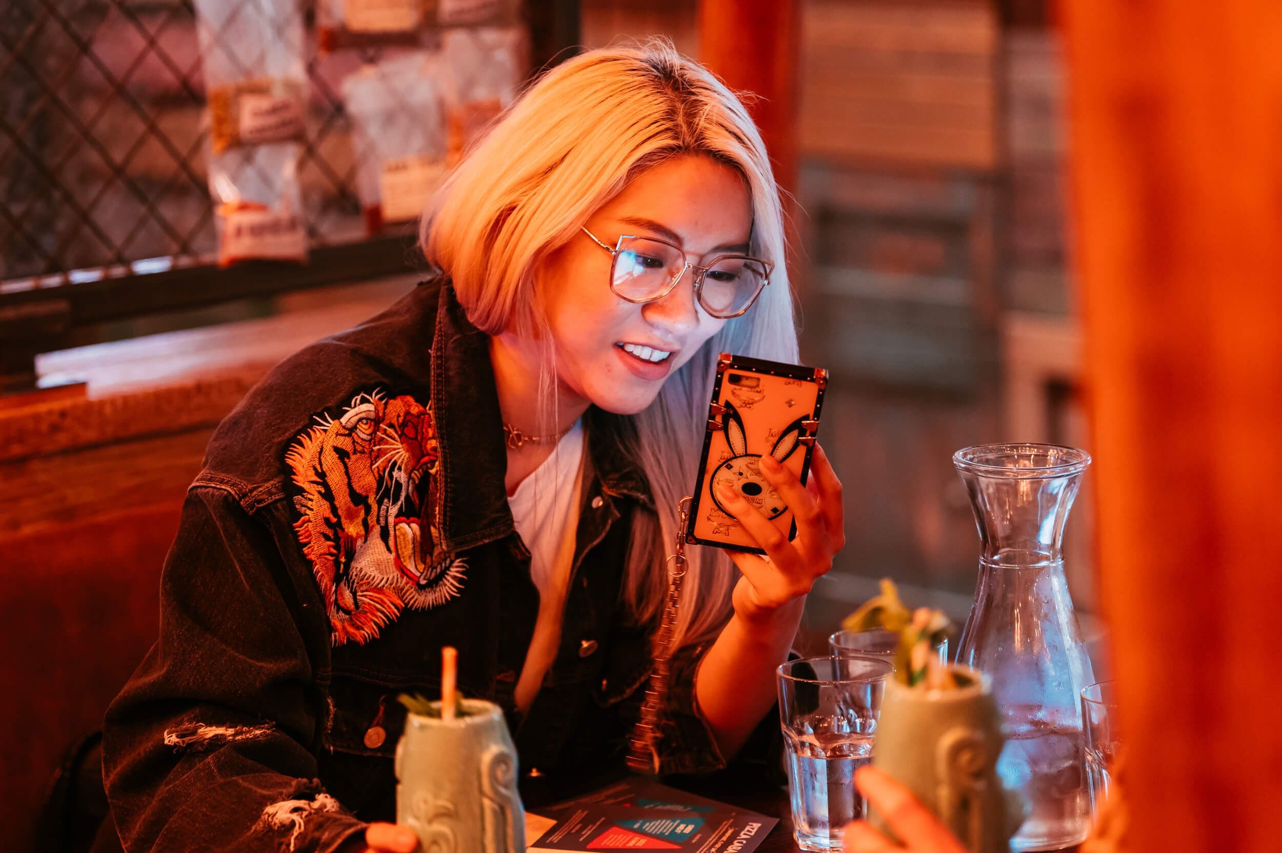 Young lady takes a picture of a cocktail.