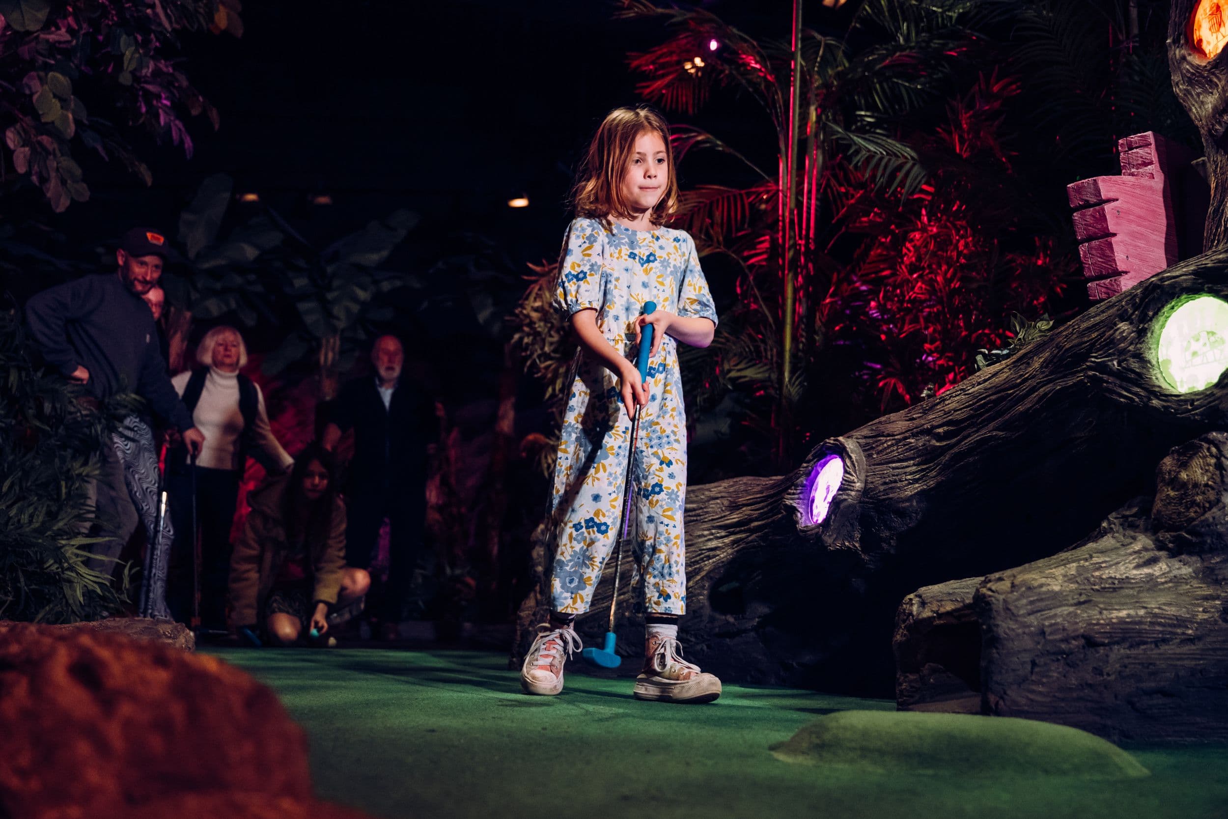 A young girl playing mini golf