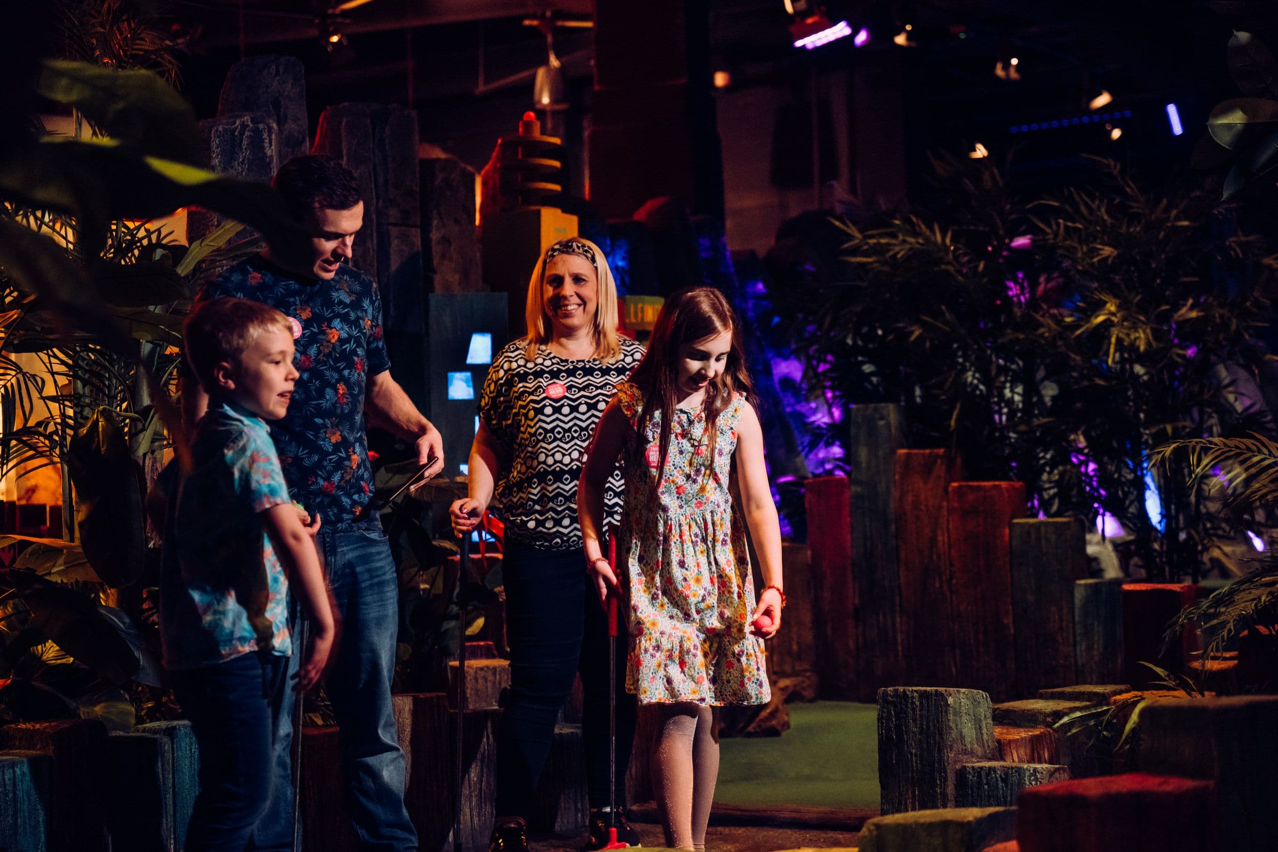 A family of 4 laughing while playing mini golf at Treetop Golf.