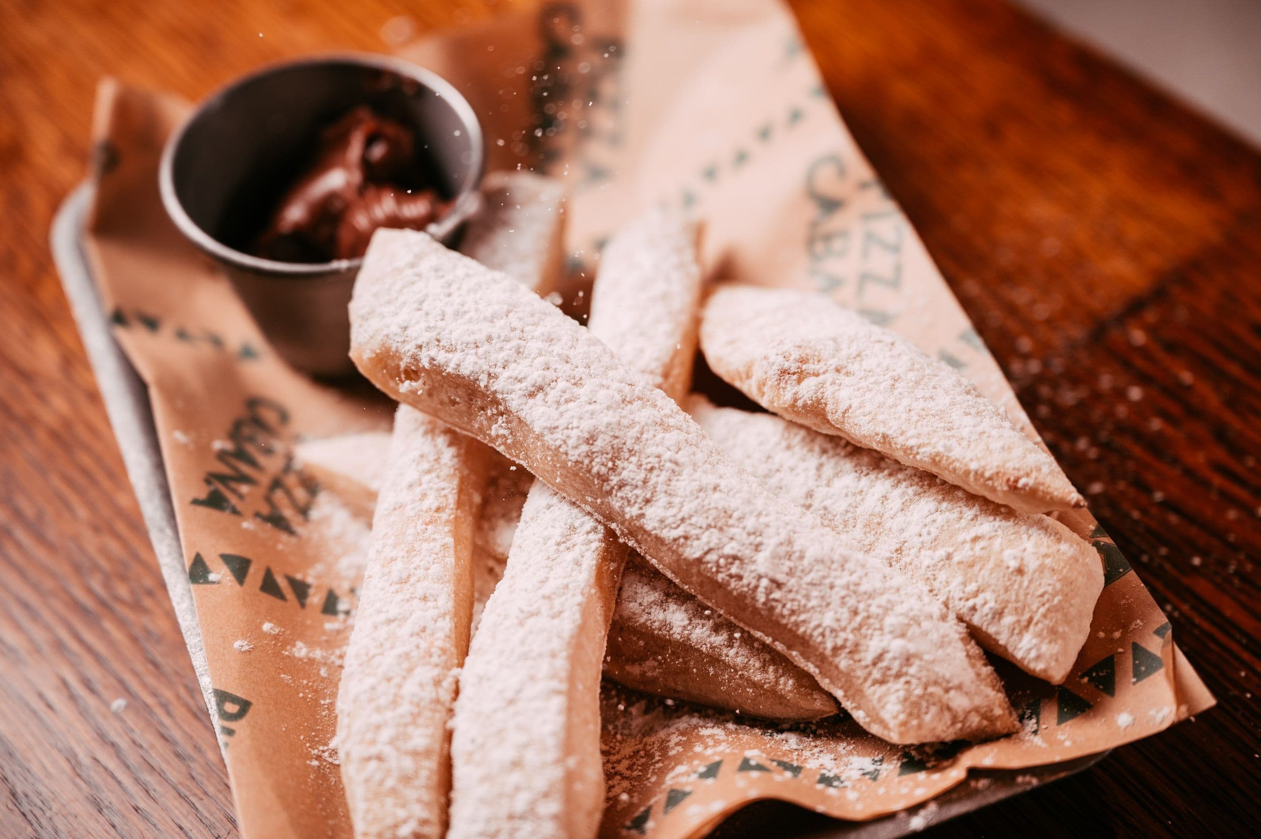 A selection of tasty dough sticks positioned next to a pot of chocolate sauce at Treetop Golf.