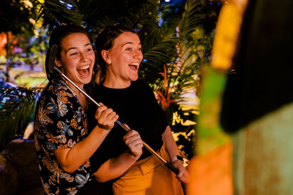 Two ladies pose at the photo booth with golf clubs in hand.