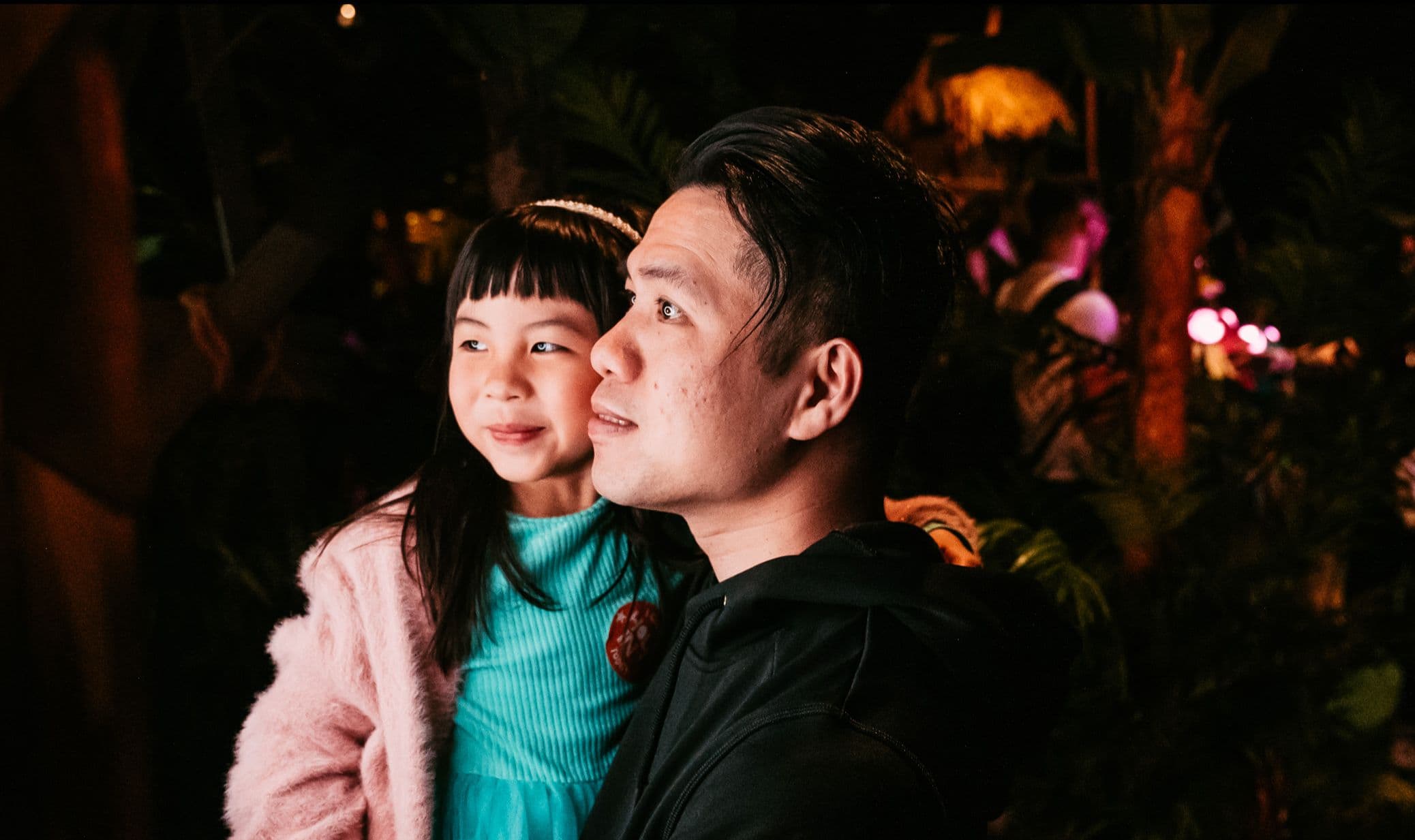 A father carrying his young daughter as they both smile for a photo at Treetop Golf.