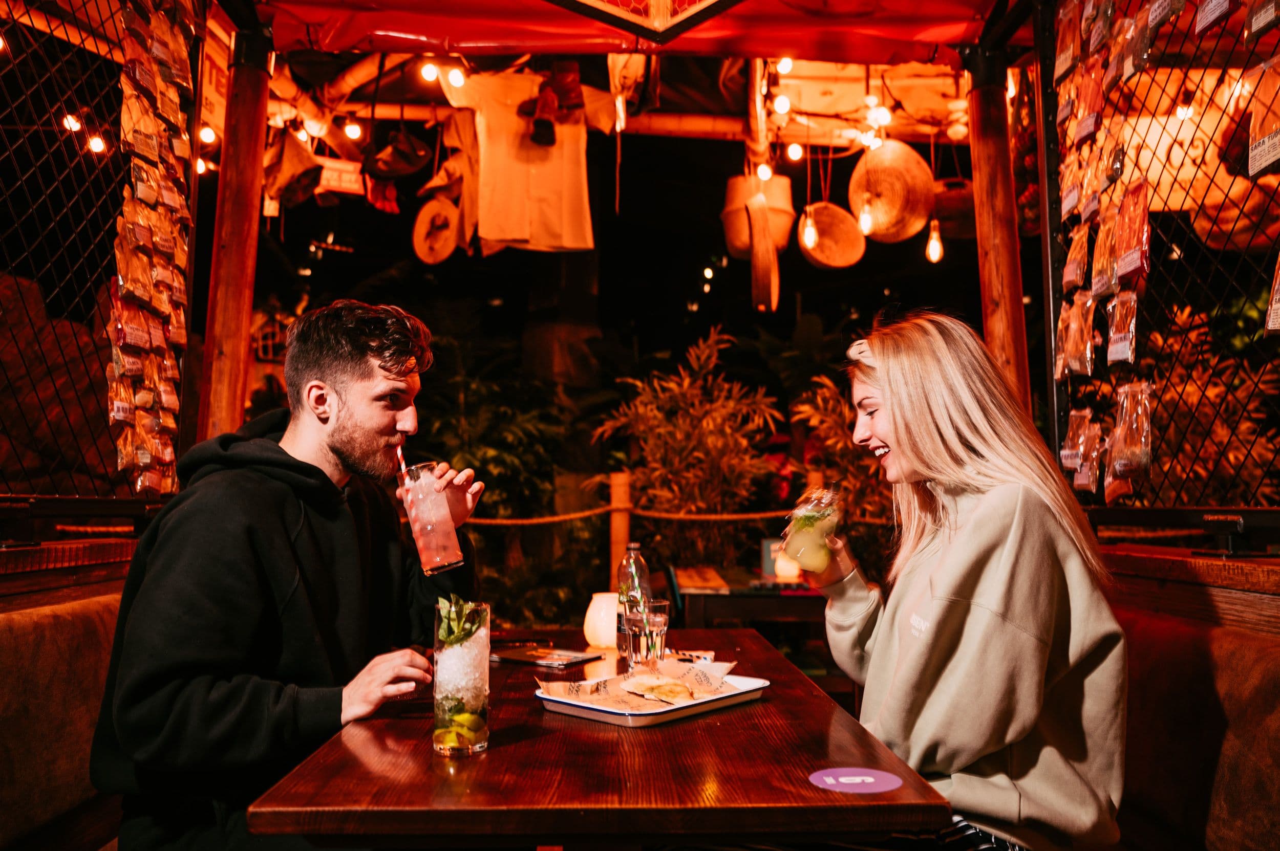 A young couple drinking and smiling at Treetop Golf.