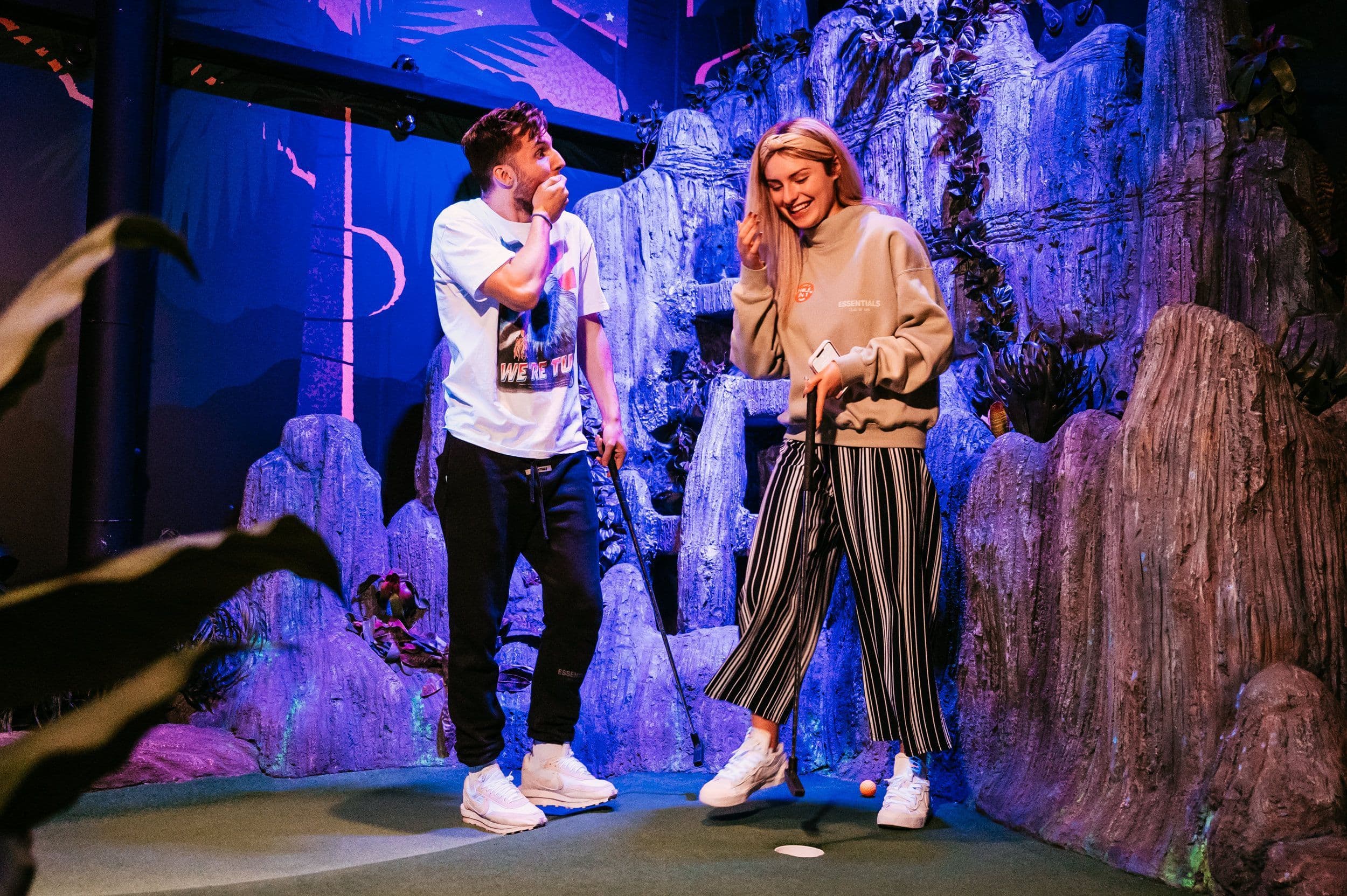 Young Couple Playing Mini Golf and Smiling.